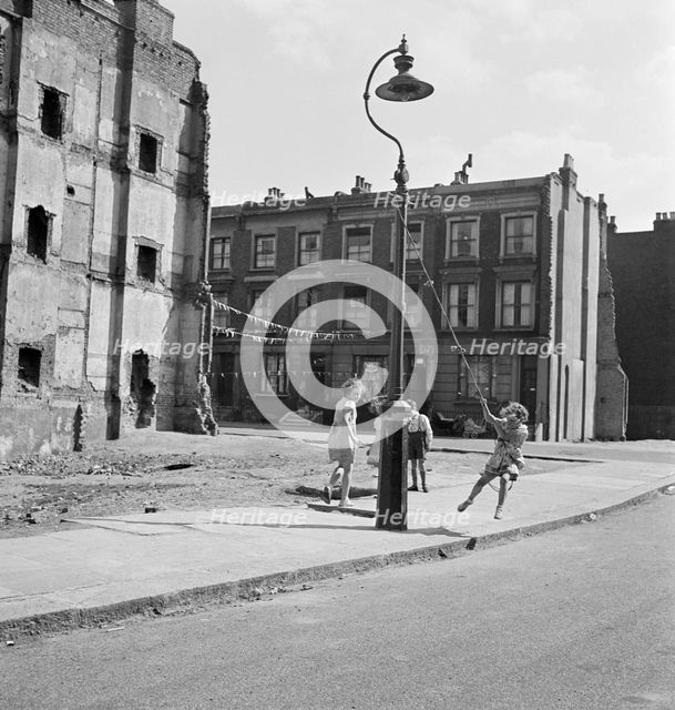 Children swinging on a lamppost, London, 1960-1965. Artist: John Gay