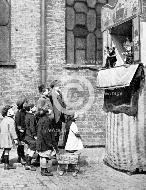 Children watching a Punch and Judy show in a London street, 1936. Artist: Donald McLeish
