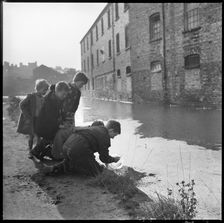 Children using a goldfish bowl to fish in the Caldon Canal, Hanley, Stoke-on-Trent, 1965-1968. Creator: Eileen Deste