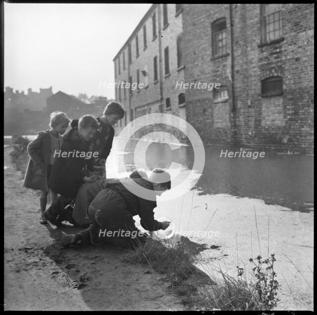Children using a goldfish bowl to fish in the Caldon Canal, Hanley, Stoke-on-Trent, 1965-1968. Creator: Eileen Deste.