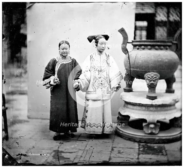 China: a Manchu woman with her maid standing beside a bronze burner, Beijing, 1869. Creator: John Thomson.
