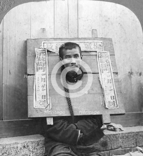 'Chinese prisoner in the cangue placarded with the record of his crime', China, 1902. Artist: CH Graves