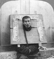 Chinese prisoner in the cangue placarded with the record of his crime China, 1902. Artist: CH Graves