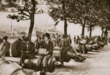 City workers lunching at Tower wharf, seated on old cannons, c1920s-c1930s