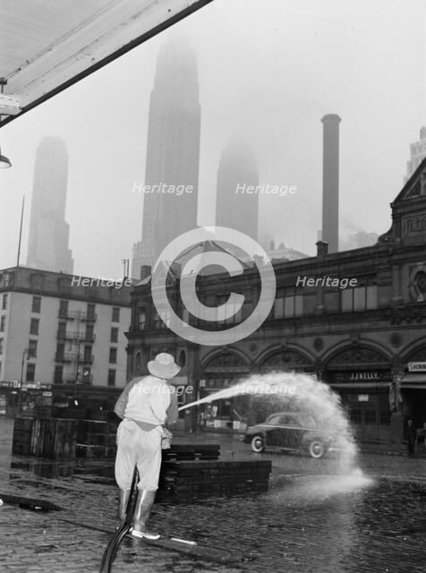 City sanitation workman washing streets at Fulton fish market, New York, 1943. Creator: Gordon Parks.