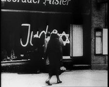 Civilians Looking at Shop Window with Graffiti Reading: Juden on it, 1933. Creator: British Pathe Ltd