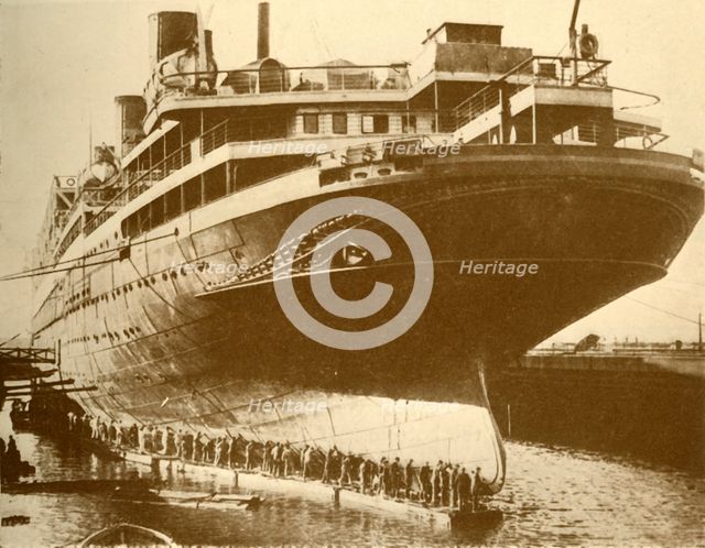 'Cleaning the Hull of the "Majestic" in Dry Dock', c1930. Creator: Unknown.