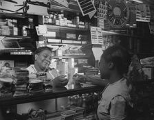 Clerk waiting on a customer in the store owned by Mr. J. Benjamin, Washington, D.C., 1942. Creator: Gordon Parks