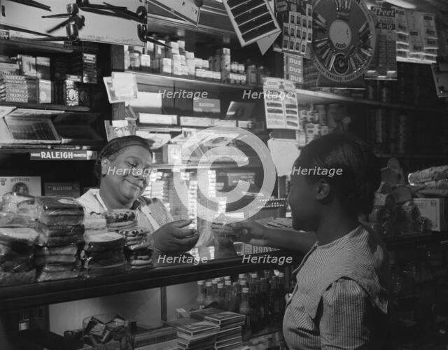 Clerk waiting on a customer in the store owned by Mr. J. Benjamin, Washington, D.C., 1942. Creator: Gordon Parks.