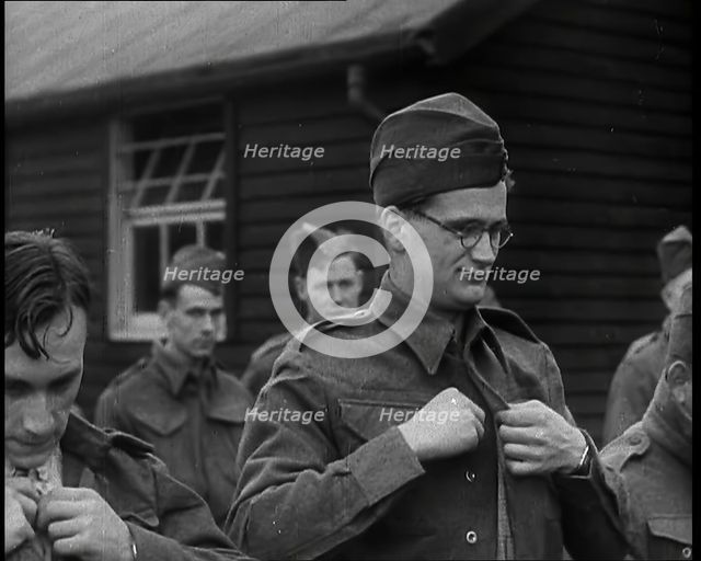 Close up on a Male British Soldier Wearing a Side Cap and Round-Rimmed Glasses Buttoning up..., 1939 Creator: British Pathe Ltd.