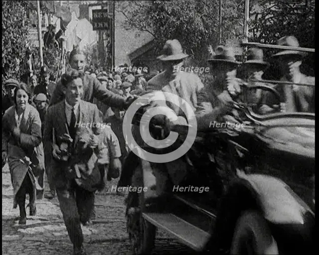 Crowd Chasing a Motorcar as It Climbs up a Hilly Cobbled Street, 1920. Creator: British Pathe Ltd.