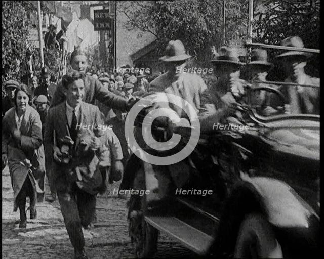 Crowd Chasing a Motorcar as It Climbs up a Hilly Cobbled Street, 1920. Creator: British Pathe Ltd.