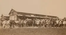 Crowds of people in front of buildings at the marketplace in the center of town..., (1899?). Creator: Eleanor Lord Pray