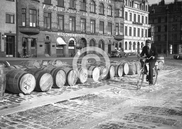 Cyclist riding through evaporated milk spilt from barrels on the quayside, Malmö, Sweden, May 1947. Artist: Otto Ohm