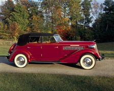 A 1936 Auburn 852 car on a gravel driveway in the autumn sunlight