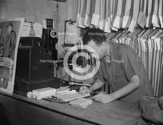 A tailor in Frank's cleaning and pressing establishment checking..., Washington, D.C., 1942. Creator: Gordon Parks.