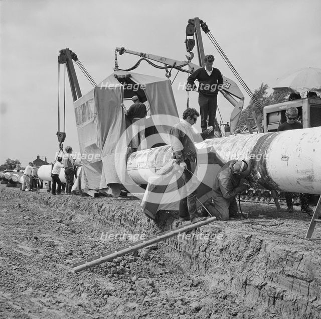 A team of men working on the lining up operation of the Fens gas pipeline, Norfolk, 24/07/1967. Creator: John Laing plc.