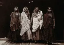 A troupe of nautch dancing girls, standing in a line holding hands, in a studio setting, c1900. Creator: Unknown