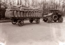 A tractor pulling a trailer loaded with sacks, 1928