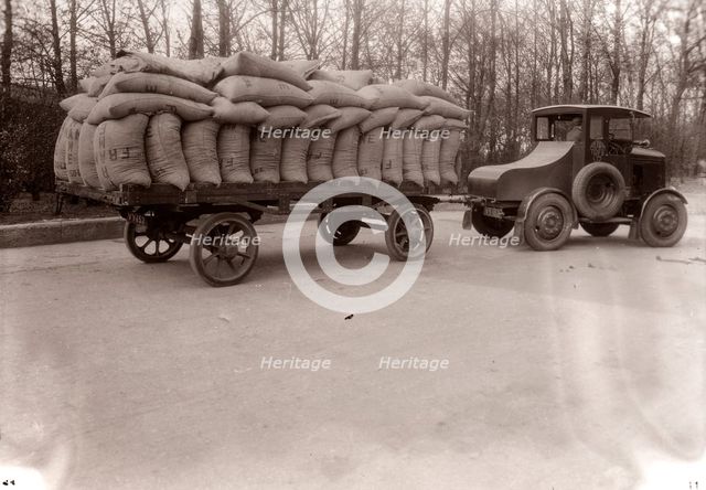 A tractor pulling a trailer loaded with sacks, 1928. Artist: Unknown