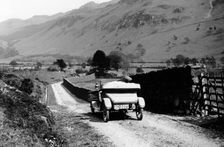 A vintage car travelling along a lane through the Lake District, Cumbria, 1920s