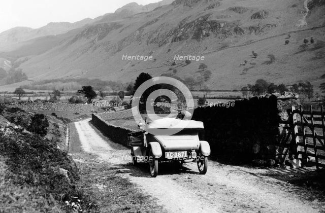 A vintage car travelling along a lane through the Lake District, Cumbria, 1920s. Artist: Unknown