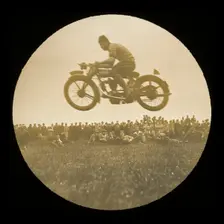A view of a motorcycle jumping in front of a crowd of onlookers at an unknown..., 1920s-1930s. Creator: Norman Kingsley Harrison