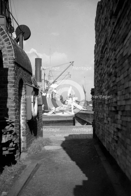 A view between harbour buildings in London docks, 1937. Artist: SW Rawlings