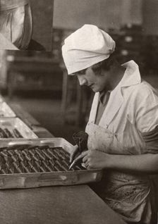 A woman uses a piping bag to decorate chocolates, Rowntree factory, York, Yorkshire, 1932