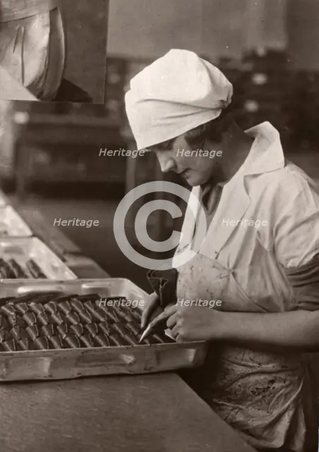 A woman uses a piping bag to decorate chocolates, Rowntree factory, York, Yorkshire, 1932. Artist: Unknown