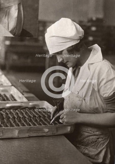 A woman uses a piping bag to decorate chocolates, Rowntree factory, York, Yorkshire, 1932. Artist: Unknown