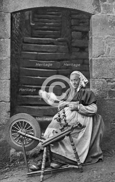 A woman at a spinning wheel, Dinan, Brittany, France, c1922. Artist: Unknown