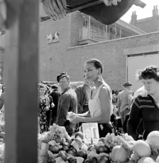 A woman buys fruit at a stall in a North London street market, c1946-c1959. Artist: John Gay