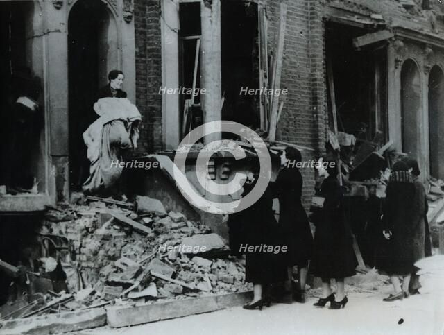A woman collects her belongings from a bombed house, London, World War II, c1940-c1945. Artist: Unknown