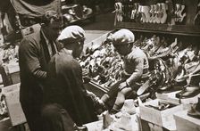 A woman from Harlem buys a pair of shoes for her child, New York, USA, c1920s-c1930s
