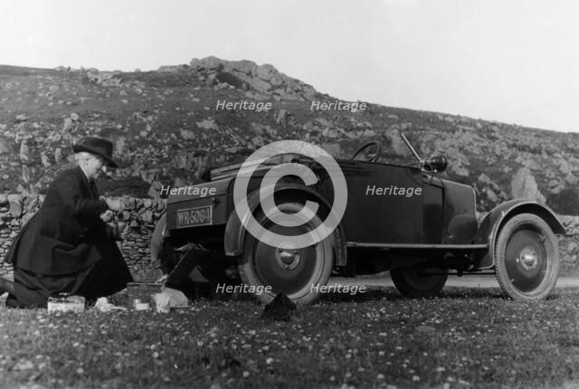 A woman picnicking next to her air-cooled Rover 8, c1919-c1925. Artist: Unknown