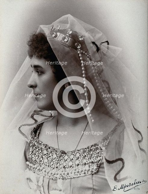 A woman posing in a photographic studio, wearing a bridal? dress and veil, in front of..., 1900-1910 Creator: Unknown.