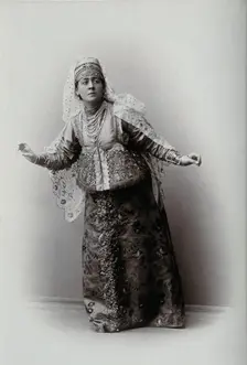 A woman posing in a photographic studio, wearing an embriodered dress, c1900s. Creator: Unknown