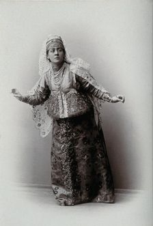 A woman posing in a photographic studio, wearing an embriodered dress, c1900s. Creator: Unknown