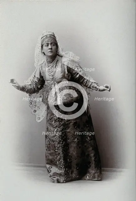 A woman posing in a photographic studio, wearing an embriodered dress, c1900s. Creator: Unknown.