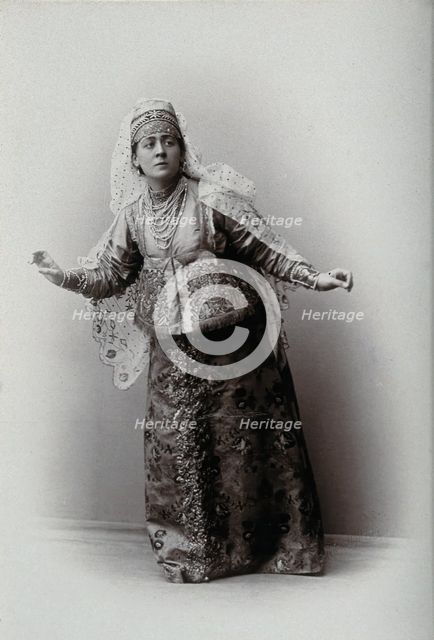 A woman posing in a photographic studio, wearing an embriodered dress, c1900s. Creator: Unknown.