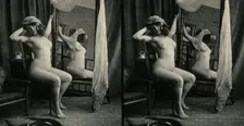 A woman posing naked in a photographic studio, sitting on a chair in front of a looking-glass, c1900 Creator: Unknown