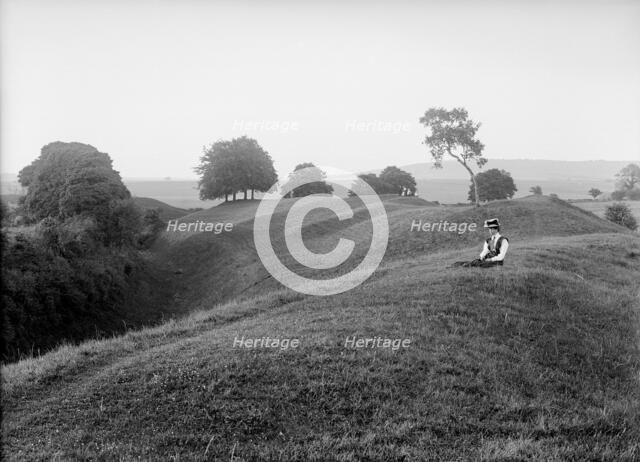 A woman sitting on the external bank at Avebury, Wiltshire, 1908. Artist: Harold St George Gray