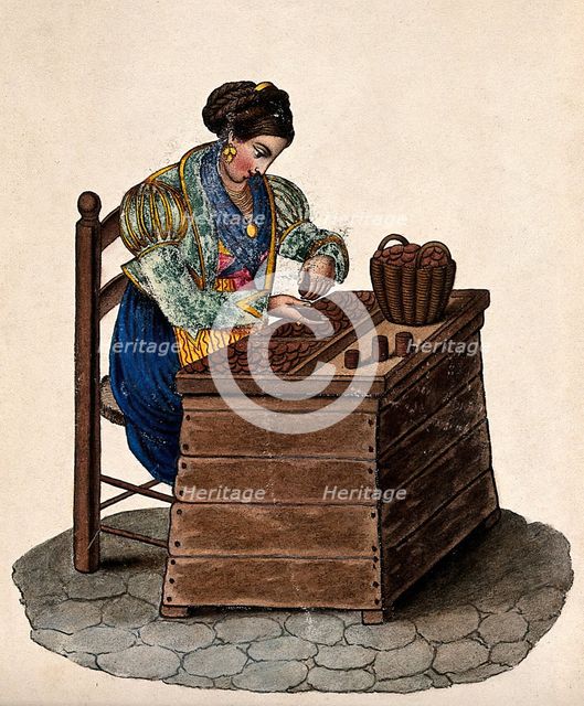 A woman sits at a wooden box counting money out of a basket onto a tray. Creator: Unknown.