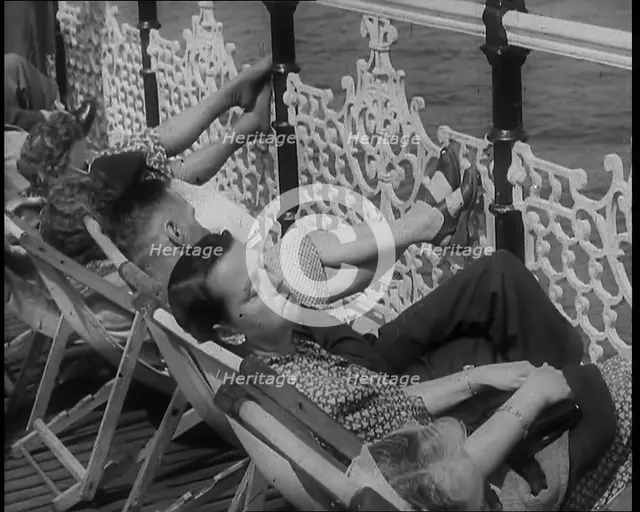 A Woman Sleeping in a Deckchair by Railings on the Promenade at Brighton With a Man and..., 1939. Creator: British Pathe Ltd.