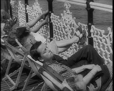 A Woman Sleeping in a Deckchair by Railings on the Promenade at Brighton With a Man and..., 1939. Creator: British Pathe Ltd