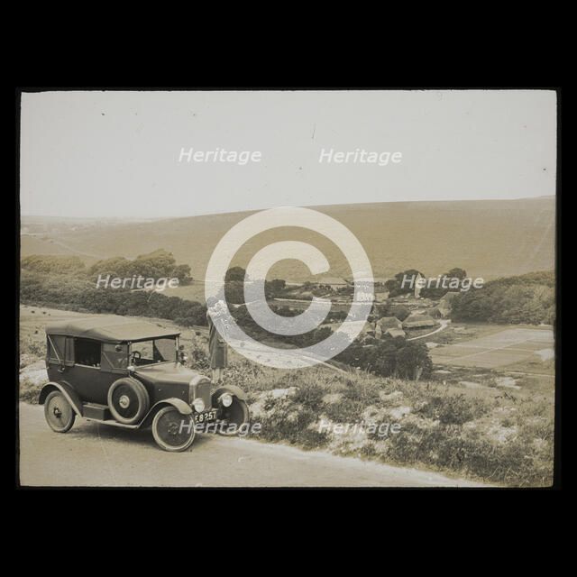 A woman standing beside a car parked on East Dean Road near Exceat Hill, looking out..., 1921-1939. Creator: Norman Kingsley Harrison.