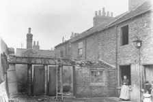 A woman stands in the back yard of a house, York, Yorkshire, 1923