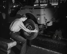 A Worker Fitting Wheels on a Car at an American Factory , 1942. Creator: British Pathe Ltd