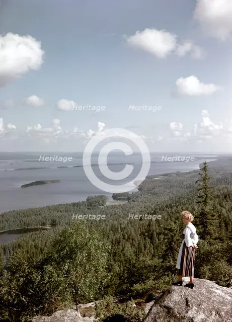 A young woman in traditional dresslooking out over Lake Pielinen, Koli district, Finland, 1960s. Creator: Göran Algård.